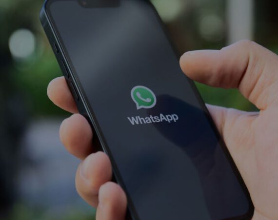 Hand holding phone with the mobile application, WhatsApp, shown on the screen