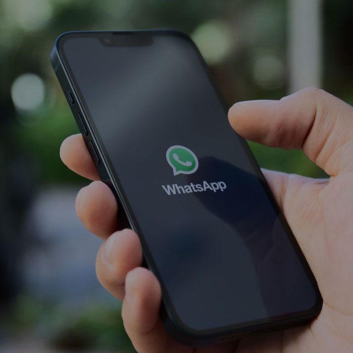 Hand holding phone with the mobile application, WhatsApp, shown on the screen